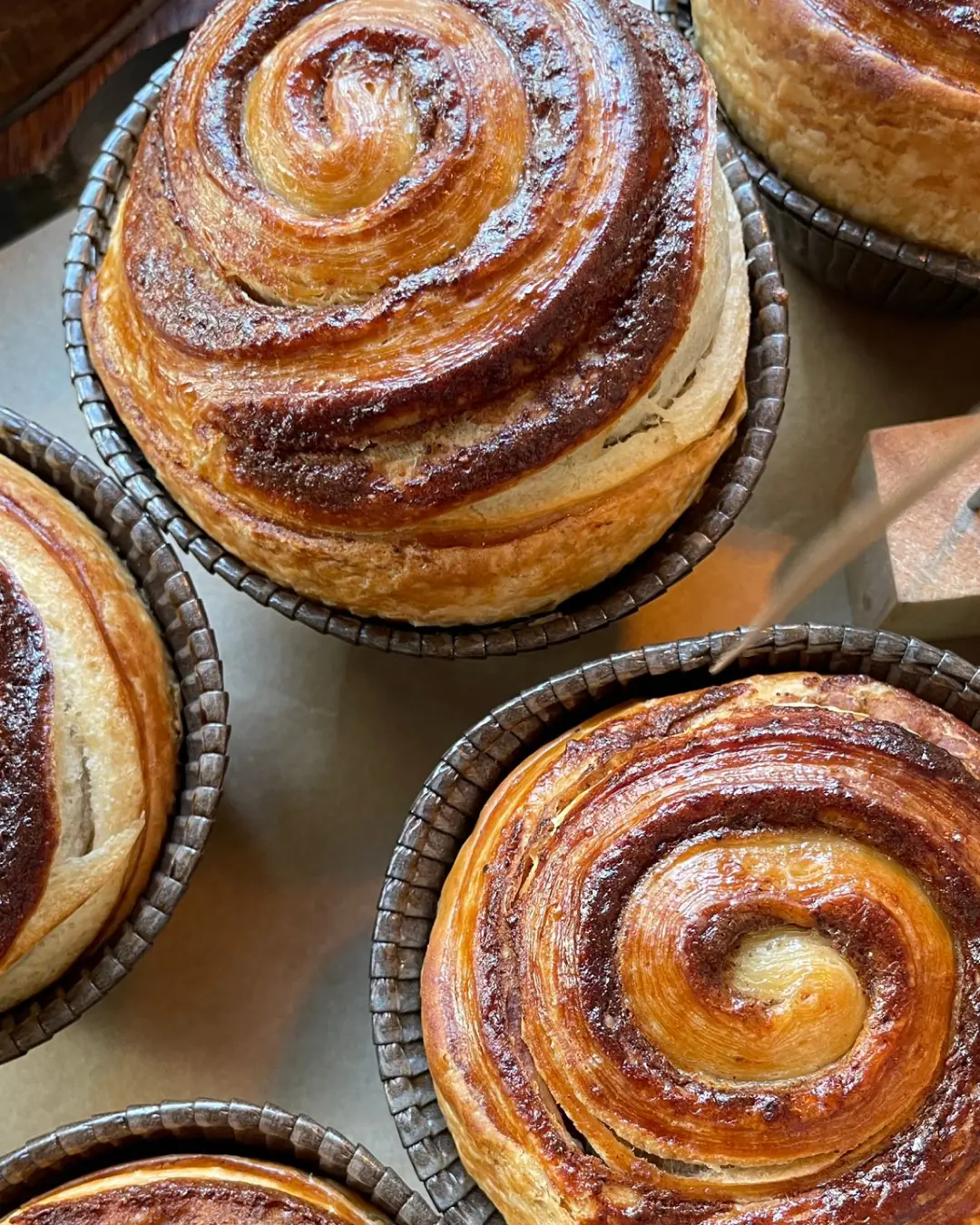 A close-up of a golden-brown cinnamon swirl pastry.