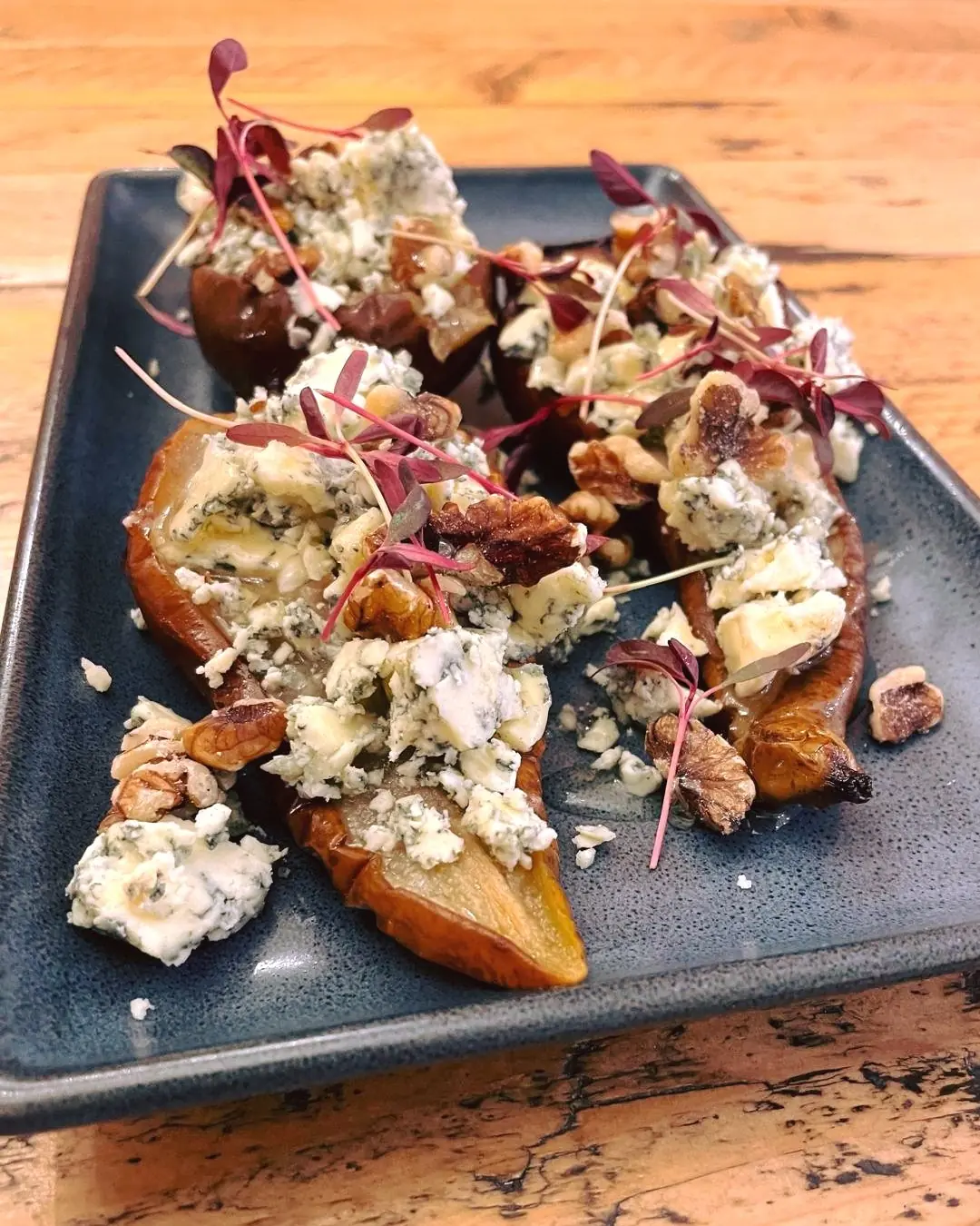 An elegant small plate with roasted pear, crumbled blue cheese, and toasted walnuts.